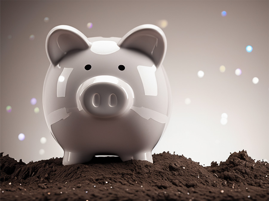 simple piggy bank standing atop a pile of dirt with a blank background. There is a hint of glinting diamonds showing through the dirt